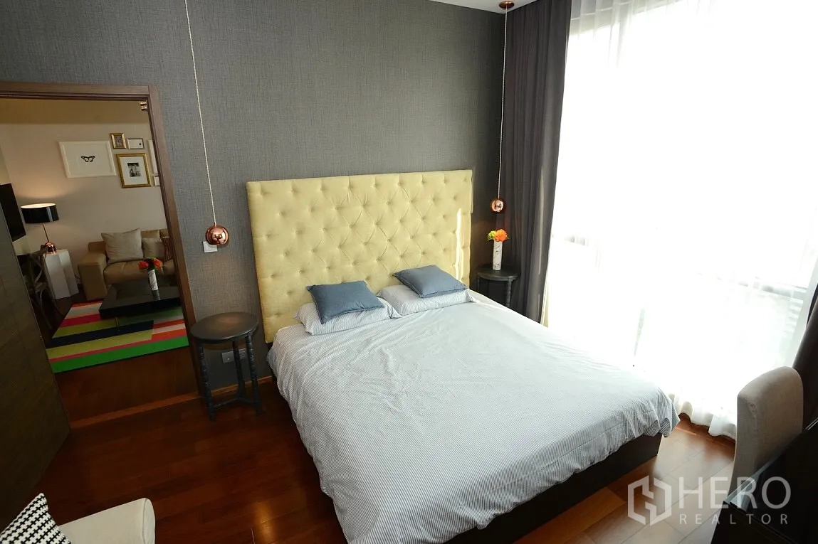 Condominium for rent in Watthana, Bangkok - Bright bedroom with large window, gray drapes, and soft headboard overlooking the living area.