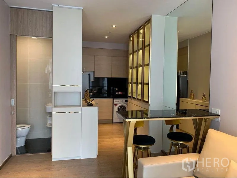 คอนโด ขาย - ครัวบิวท์อินท็อปสีดำ ตู้เก็บของ เครื่องซักผ้า และประตูห้องน้ำใกล้กัน