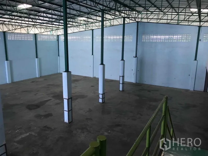 คลังสินค้า ให้เช่าในBang Phli, Samut Prakan - มุมมองจากที่สูงเห็นพื้นโกดังโล่ง เสาโครงเหล็กสีเขียว และผนังสูงมีช่องลม