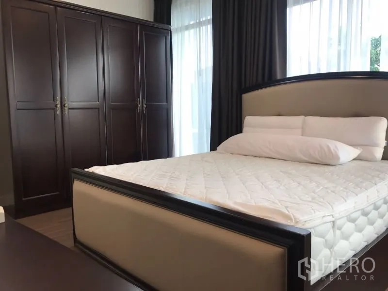 Detached House for rent in Bang Kapi, Bangkok - Cozy bedroom with double bed, dark wood wardrobe and sheer curtains.