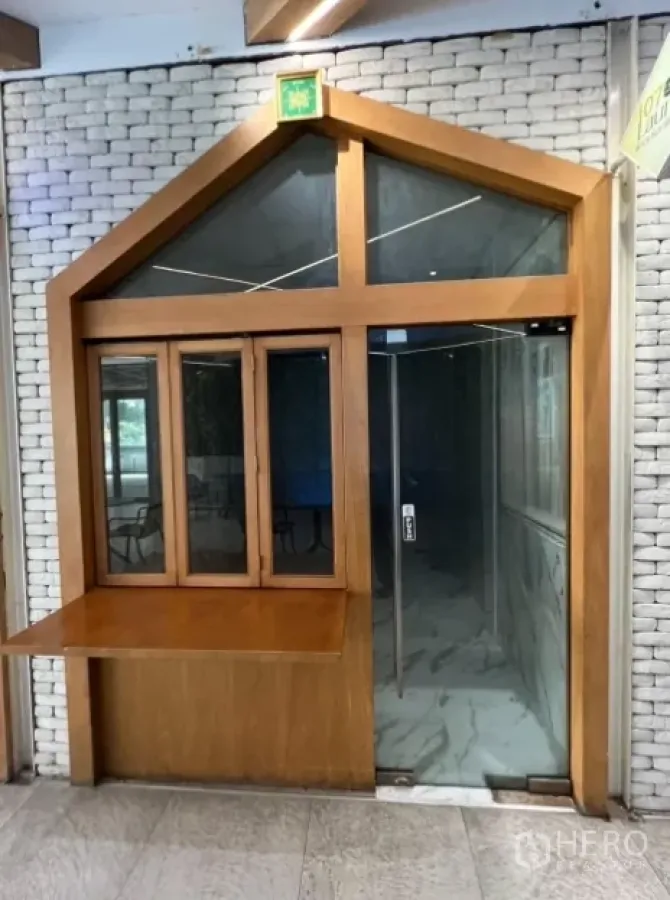 零售空间 出租在Watthana, Bangkok - 室内走廊旁的小型店面，木质框架玻璃门，带外卖窗口。