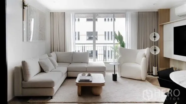 Condominium for sale in Ratchathewi, Bangkok - Another angle of the bright living room with L-shaped sofa and balcony doors.