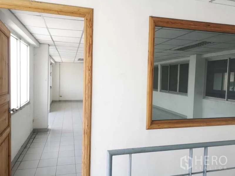 Factory for sale in Khlong Luang, Pathum Thani - Hallway with wood-trimmed internal window and door leading to office area.