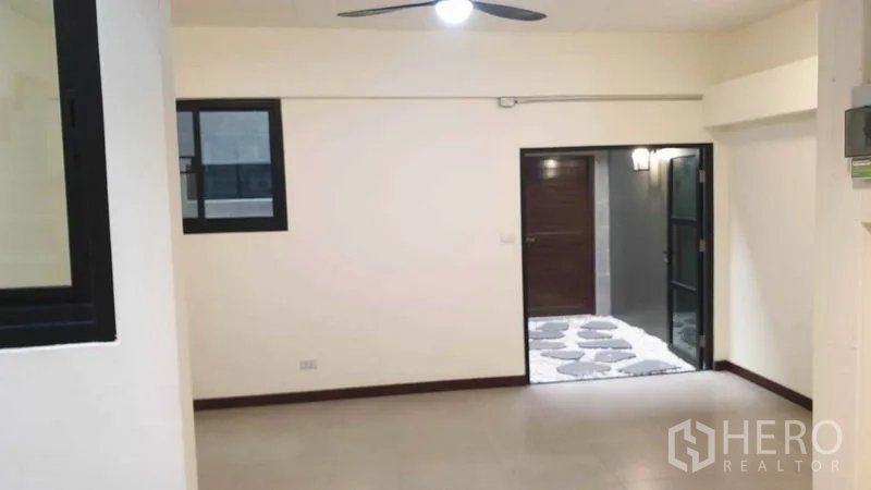 ทาวน์เฮาส์ ให้เช่าหรือขายในKhlong Toei, Bangkok - พื้นที่นั่งเล่นหน้าบ้านมีพัดลมเพดานและทางออกสู่ลานเล็ก