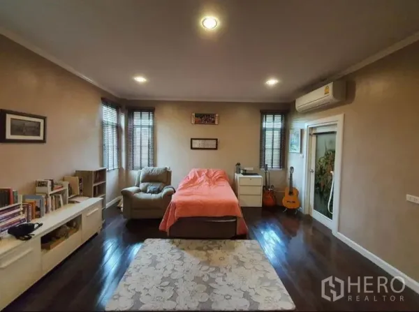 独立式住宅 出售在Sai Mai, Bangkok - 卧室配木地板、单人沙发、书架与空调。