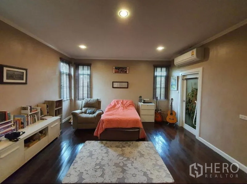 独立式住宅 出售在Sai Mai, Bangkok - 卧室配木地板、单人沙发、书架与空调。