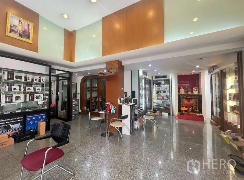 店屋 出租 - 明亮的一层展厅，玻璃展示柜、座椅与抛光石材地面。