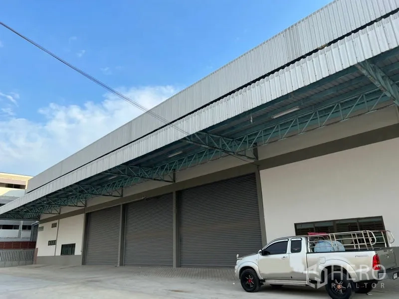 คลังสินค้า ให้เช่าในLat Krabang, Bangkok - ด้านหน้าโกดังพร้อมประตูม้วนหลายบานและชานโหลดสินค้ามีหลังคา รถกระบะจอดบนลานคอนกรีต