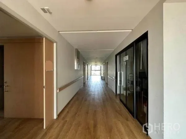 独立商业地产 出租在Bang Kapi, Bangkok - 长走道配扶手与玻璃房面，木地板贯通至尽头自然采光。