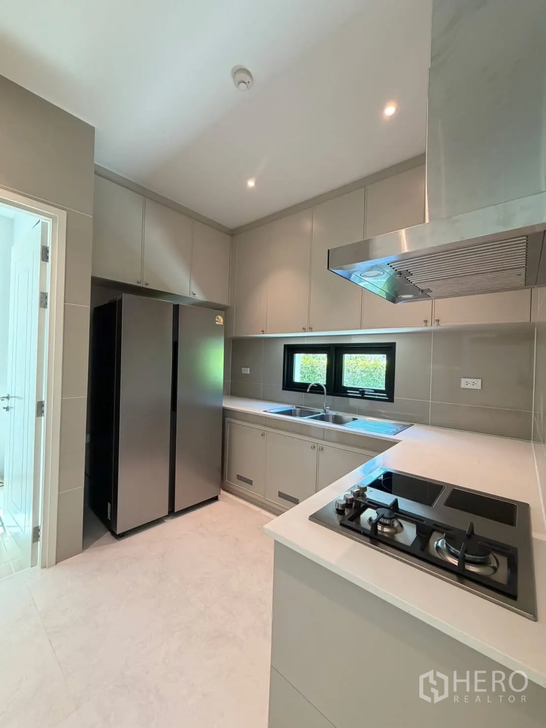 Detached House for rent in Saphan Sung, Bangkok - Modern kitchen with gas hob, stainless hood, double sink, and double-door fridge.