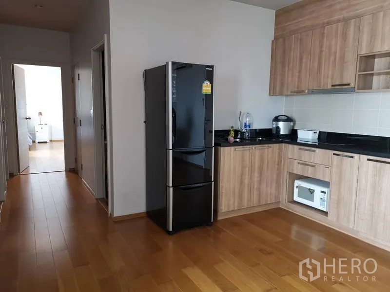 คอนโด ให้เช่าในKhlong San, Bangkok - ครัวเปิดบิลต์อินตู้ไม้ เคาน์เตอร์หินสีดำ และตู้เย็นขนาดใหญ่