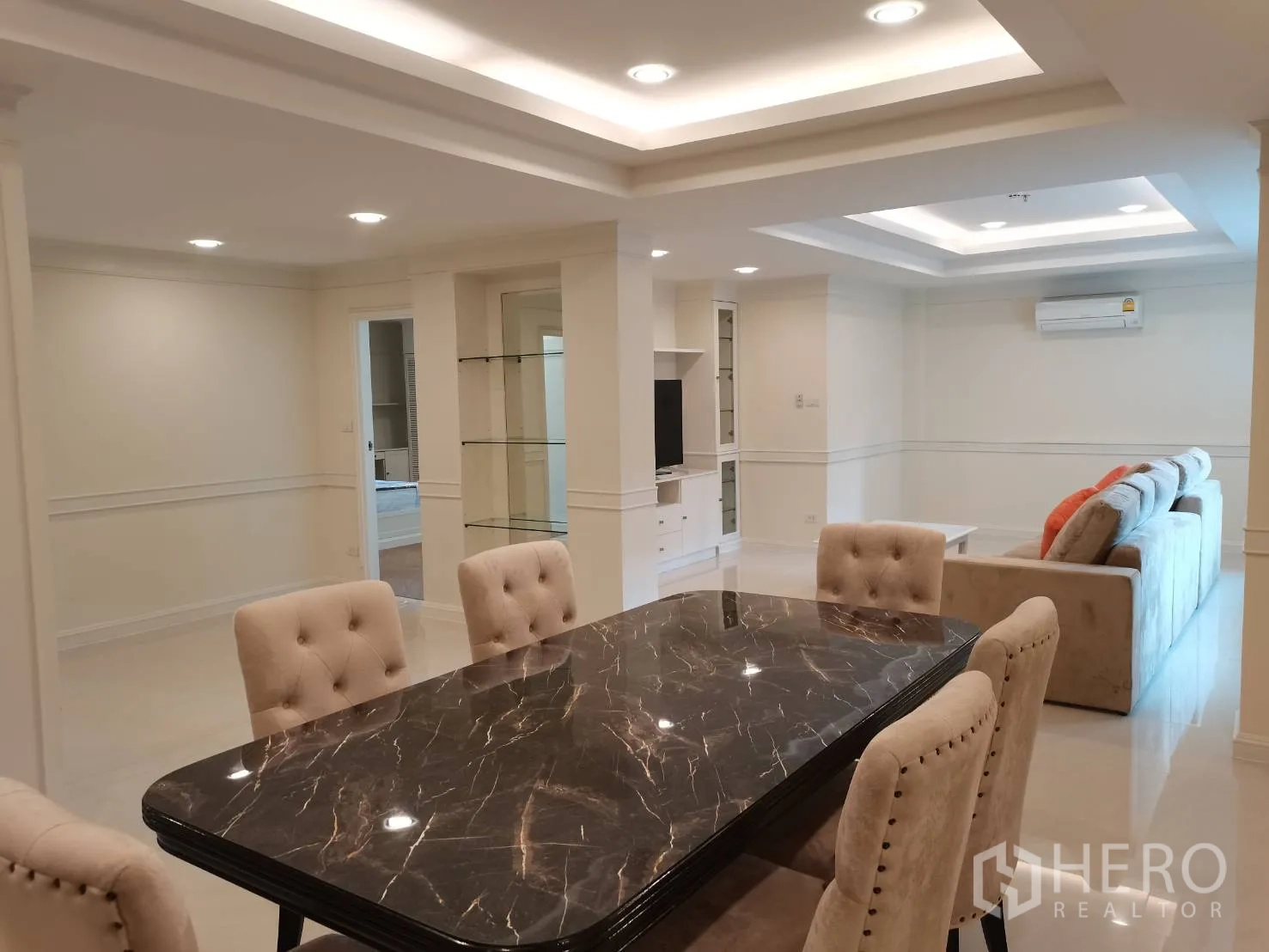 Condominium for rent in Watthana, Bangkok - Elegant dining area with a dark marble-top table and upholstered chairs under recessed lighting.