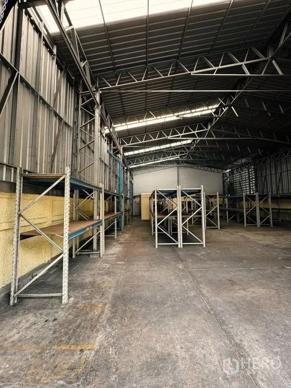 Warehouse for rent in Din Daeng, Bangkok - Aisle along wall-mounted shelving with steel columns and open floor space in the warehouse.