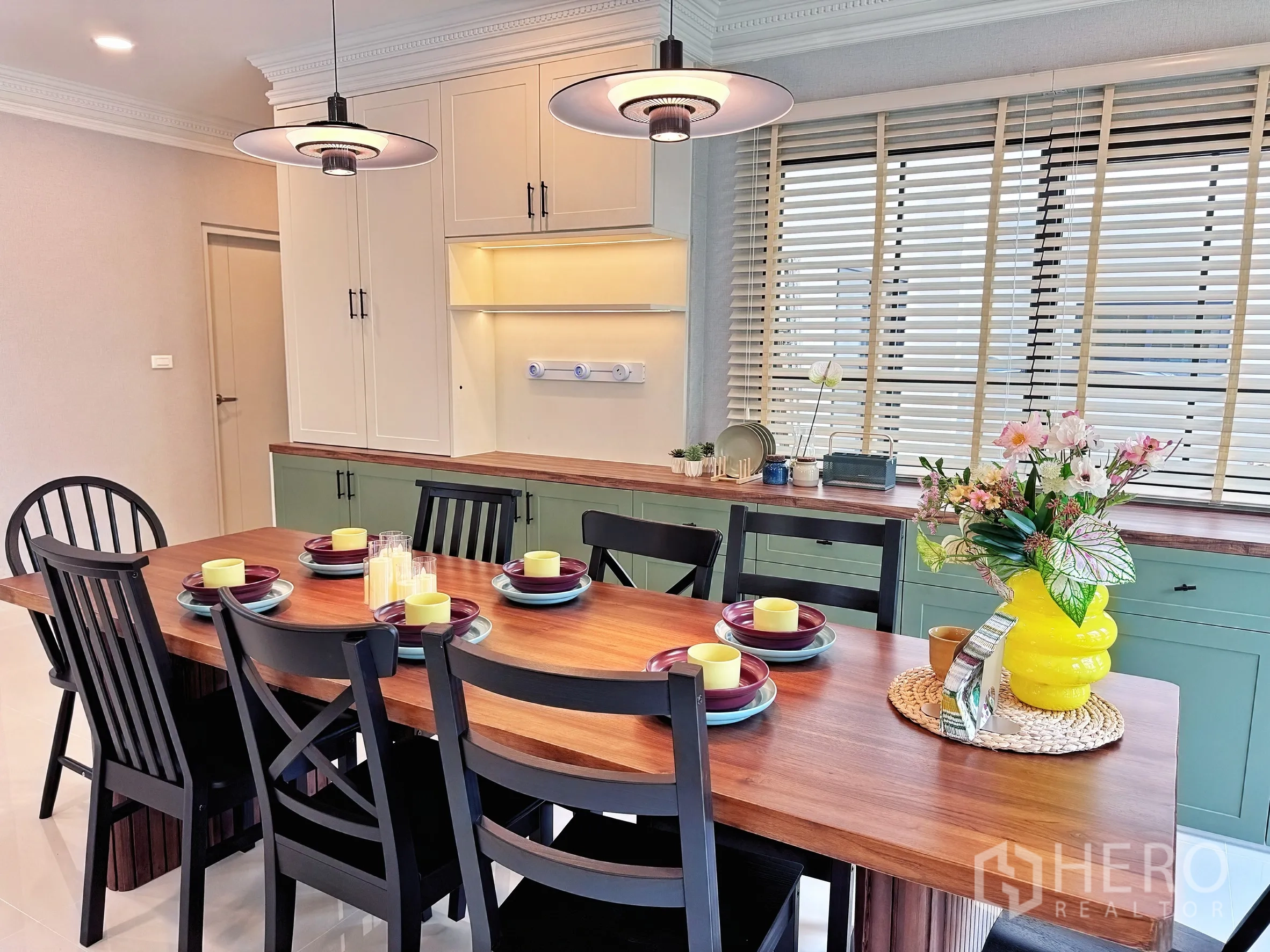 Detached House for rent in Bang Phli, Samut Prakan - Dining area set for six under pendant lights, long countertop and shaker cabinets by the window.