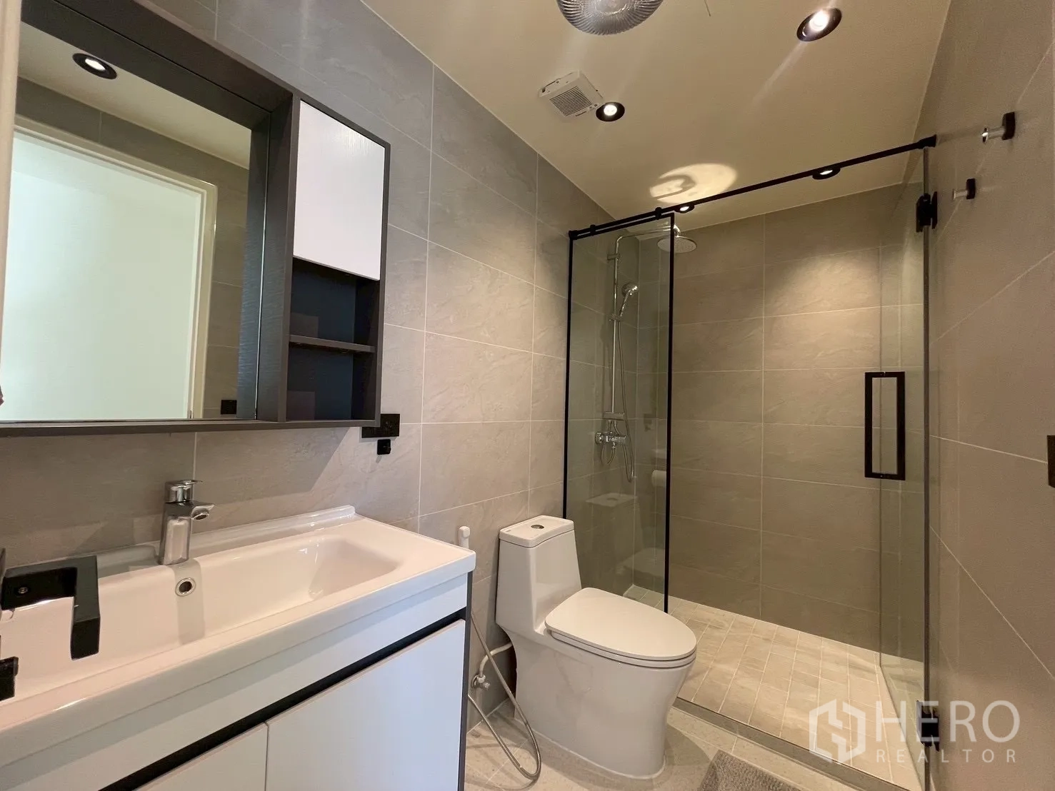 Condominium for sale in Watthana, Bangkok - Modern bathroom with wide vanity, toilet, and large walk-in shower.