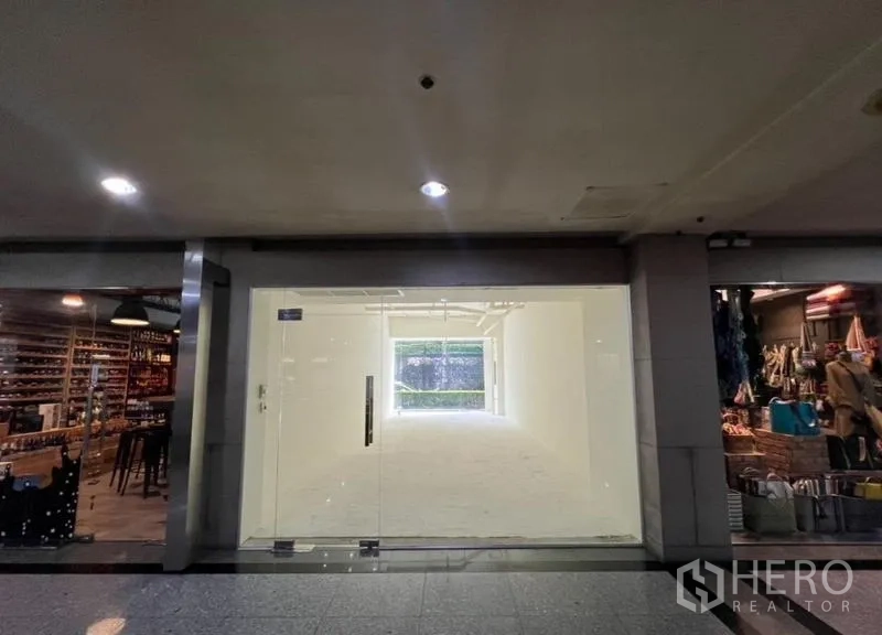 零售空间 出租在Watthana, Bangkok - 空置白盒子铺面正面图，整面玻璃门位于相邻商铺之间。