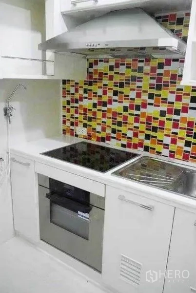 公寓 出租在Ratchathewi, Bangkok - 白色独立厨房，彩色马赛克墙面，电磁炉、烤箱、油烟机与水槽。