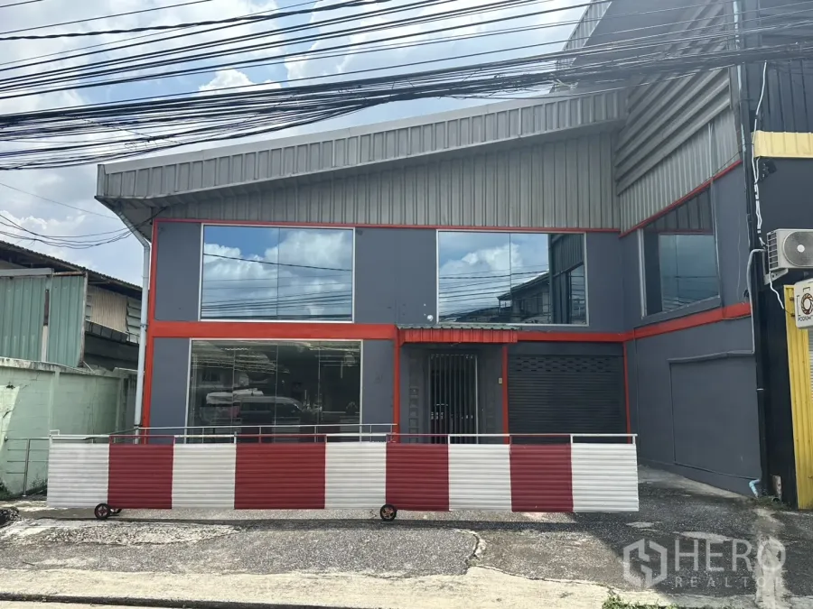 Warehouse for rent in Suan Luang, Bangkok - Street-facing two-storey warehouse facade with grey cladding, red trim and large glass windows in Suan Luang.