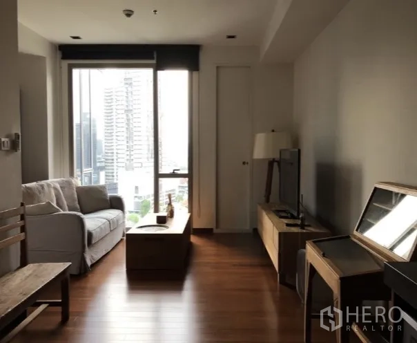 คอนโด ให้เช่าหรือขายในKhlong Toei, Bangkok - โถงรับแขกแบบโอเพ่นพร้อมตู้ทีวีและหน้าต่างสูงจากพื้นจรดเพดานมองเห็นวิวเมืองและต้นไม้