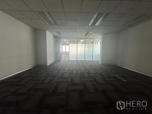 Office Space for rent in Khlong Toei, Bangkok - Work area facing a frosted glass partition and doorway with carpeted floors.
