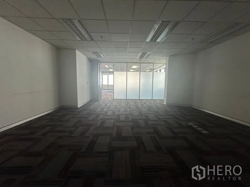 Office Space for rent in Khlong Toei, Bangkok - Work area facing a frosted glass partition and doorway with carpeted floors.
