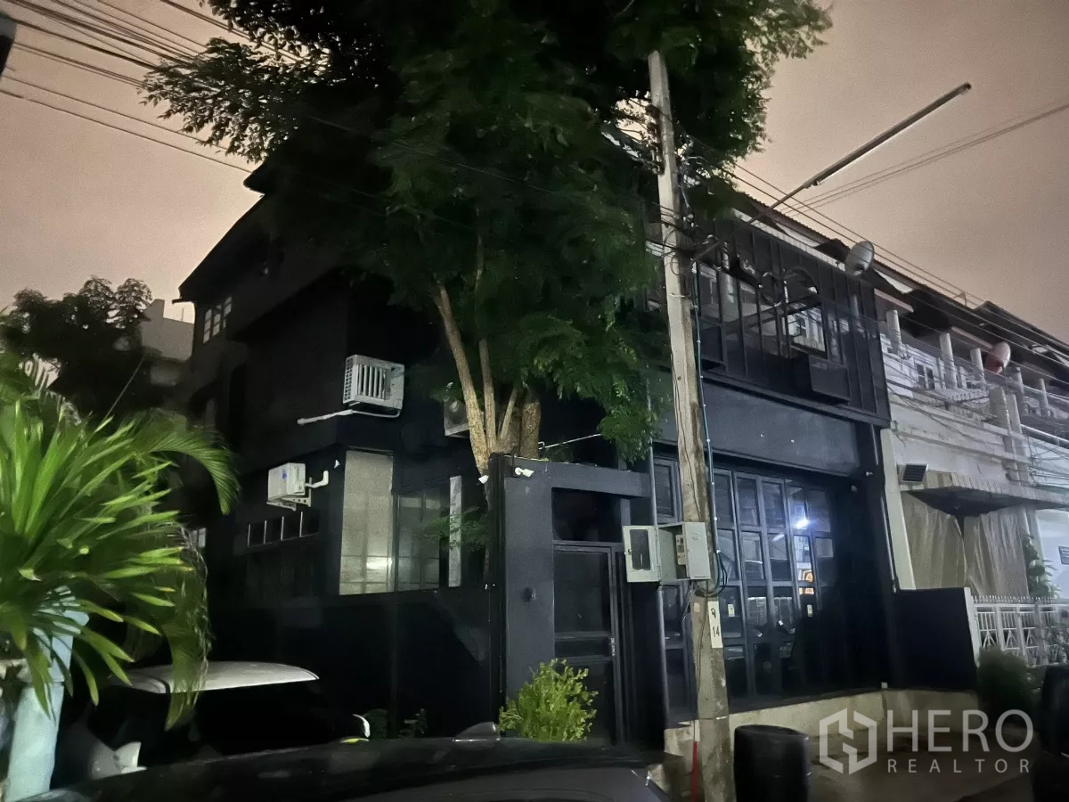 Home Office for rent in Wang Thonglang, Bangkok - Night view of the building exterior with a tree and glass frontage.