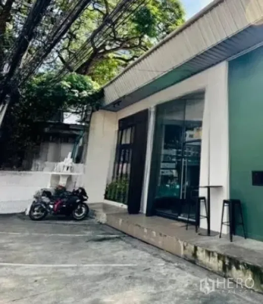 พื้นที่ขายปลีก ให้เช่าในWatthana, Bangkok - มุมด้านข้าง มีที่จอดรถและรถมอเตอร์ไซค์ หน้าร้านกระจก ใต้ร่มไม้ใหญ่