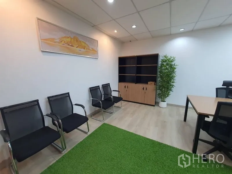 办公空间 出租 - 等候区配三把黑色网椅、木质收纳柜与绿植，旁有工作桌。