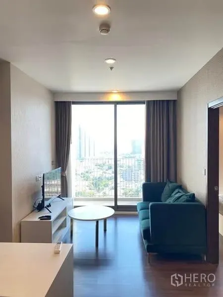 Condominium for rent - Bright living room at Whizdom Inspire Sukhumvit 101 with floor‑to‑ceiling window, sofa, TV unit and city view balcony.