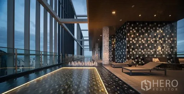 Condominium for sale in Khlong Toei, Bangkok - Sky deck with reflective water feature, sun loungers, and panoramic skyline views.