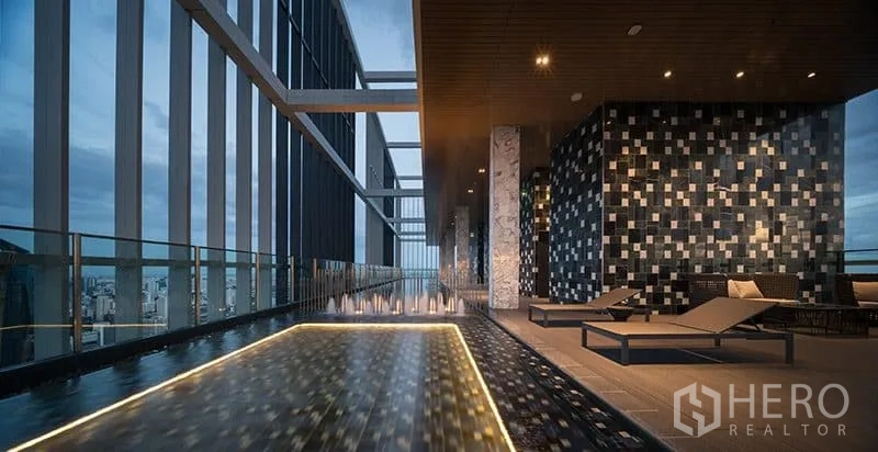 Condominium for sale in Khlong Toei, Bangkok - Sky deck with reflective water feature, sun loungers, and panoramic skyline views.