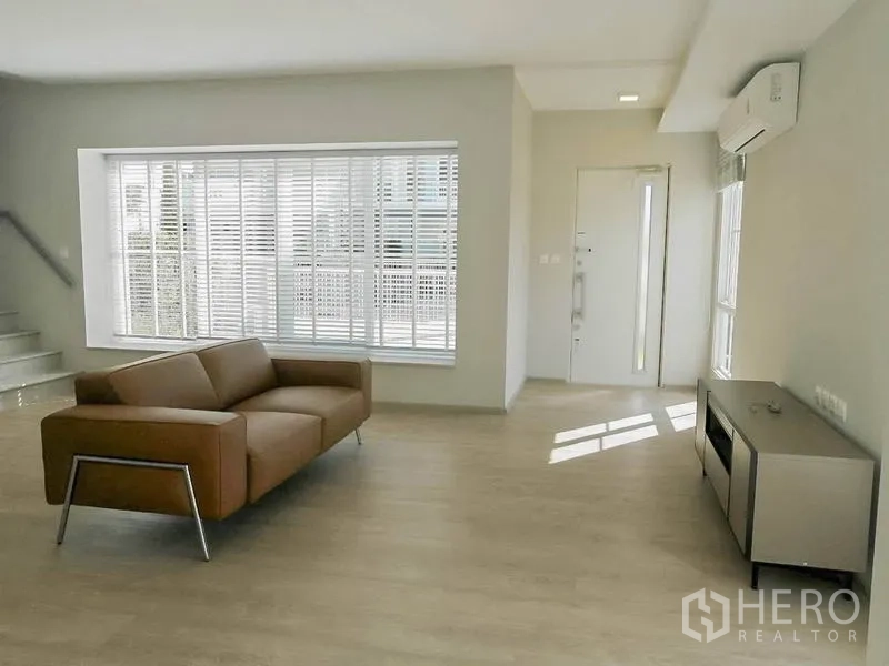 联排别墅 出租在Prawet, Bangkok - 开放式客厅视角，飘窗、楼梯与入户门，阳光充沛。