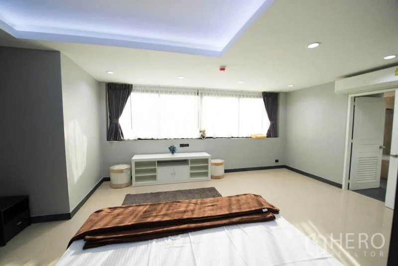 公寓 出租在Khlong Toei, Bangkok - 宽敞主卧，整面采光窗、矮柜储物与亮面地坪。