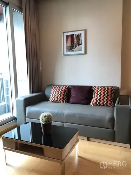 公寓 出租在Ratchathewi, Bangkok - 明亮客厅，灰色沙发、玻璃茶几与通阳台的推拉门