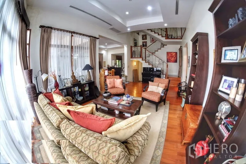 บ้าน ให้เช่าในWatthana, Bangkok - โถงรับแขกแบบเปิด โซฟา ชั้นหนังสือ และบันไดไม้เด่น