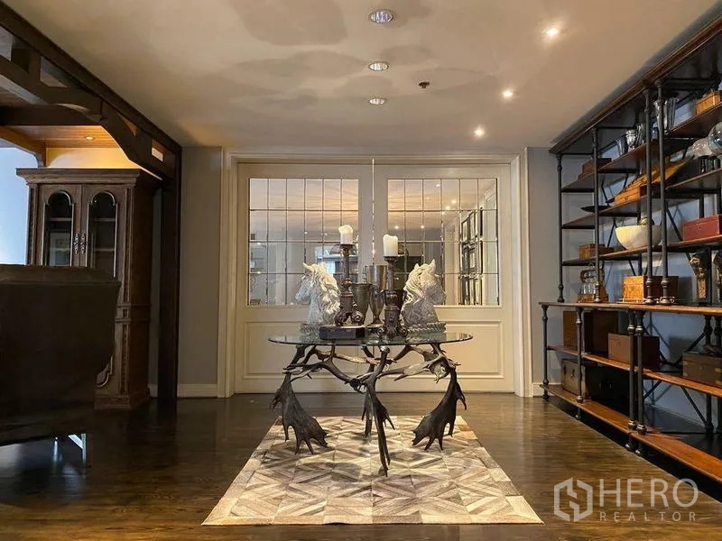 Condominium for rent in Khlong San, Bangkok - Entry foyer with sculptural round table, open shelving and paneled glass doors.