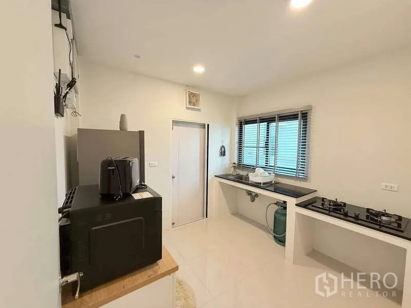 Detached House for sale in Bang Phli, Samut Prakan - Thai kitchen with counters, sink, appliances and a bright window.