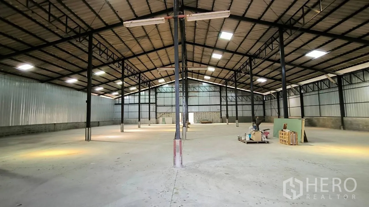 Factory for rent in Mueang Samut Prakan, Samut Prakan - Expansive factory hall with steel beams, high roof, skylights, and smooth concrete floor.