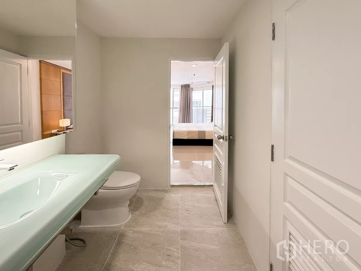 公寓 出租在Khlong Toei, Bangkok - 套内浴室，薄荷色玻璃台盆、大镜子，可见卧室视角。