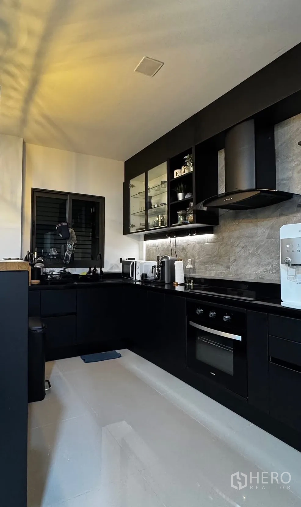 Townhouse for rent in Bang Phli, Samut Prakan - Modern black L-shaped kitchen with built-in oven, cooktop, and hood.