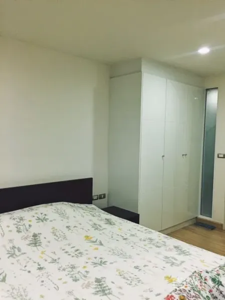 Condominium for rent or sale in Watthana, Bangkok - Cozy bedroom with built-in wardrobe and patterned bedding.
