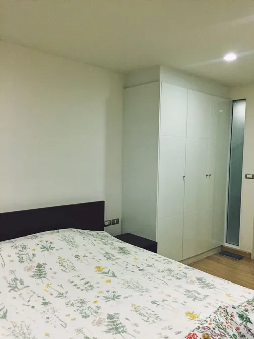 Condominium for rent or sale in Watthana, Bangkok - Cozy bedroom with built-in wardrobe and patterned bedding.