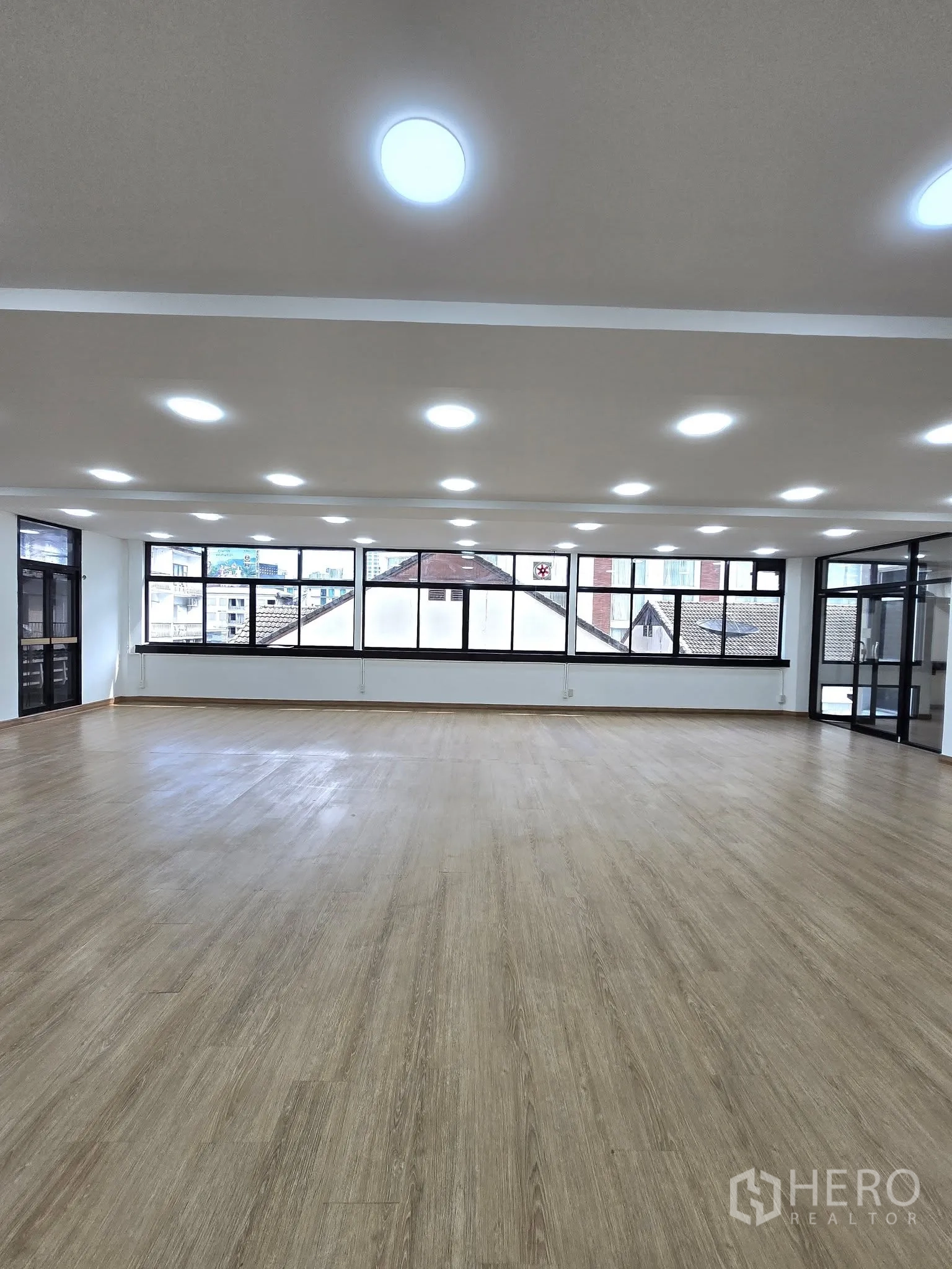 Office Space for rent in Khlong Toei, Bangkok - Spacious office hall with bright lighting and a wall of windows providing natural light.