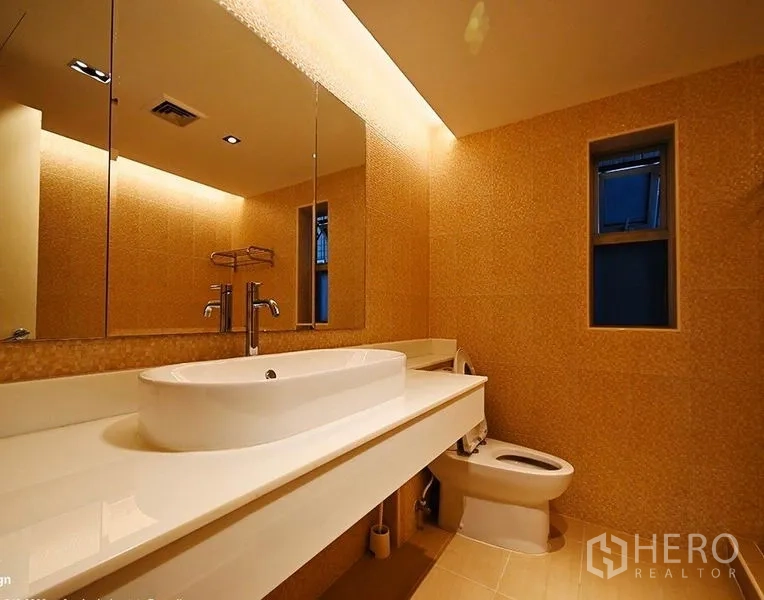 Condominium for rent in Pathum Wan, Bangkok - Bathroom with long white vanity, backlit mirror, and compact window.