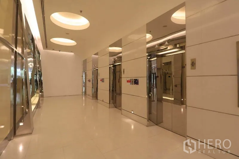 办公空间 出租在Bang Rak, Bangkok - 现代电梯大堂，配多部不锈钢电梯与圆形嵌灯。