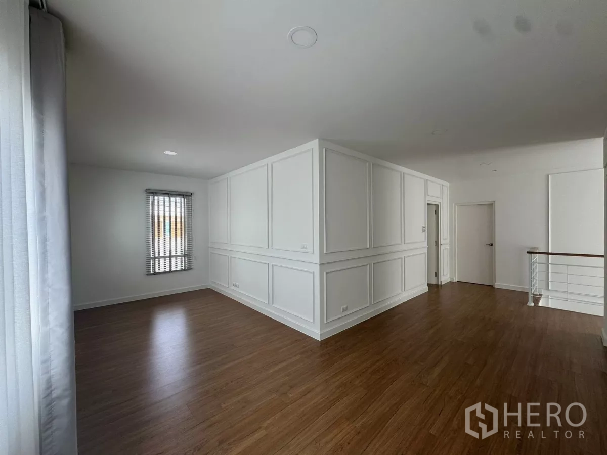 Detached House for rent or sale in Bang Bo, Samut Prakan - Spacious upstairs family area beside staircase with paneled walls and wood flooring.