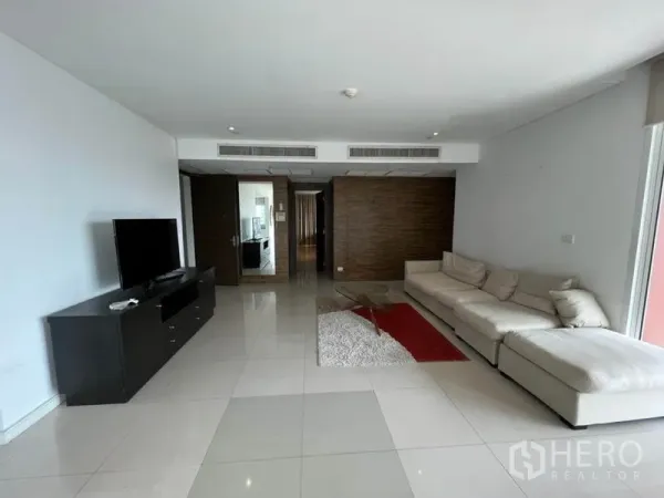 คอนโด ให้เช่าในWatthana, Bangkok - มุมมองห้องนั่งเล่นไปทางทางเข้า พร้อมโซฟาสีครีม ชั้นวางทีวี และระบบแอร์ฝังฝ้า