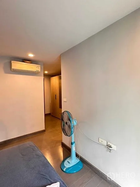 คอนโด ให้เช่า - มุมห้องนอนมีแอร์ติดผนังและทางเดินไปโซนตู้เสื้อผ้า
