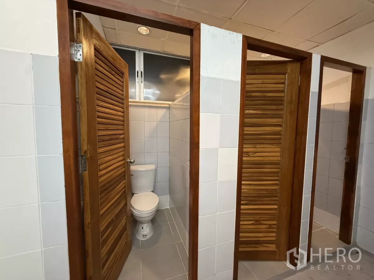 Office Space for rent in Wang Thonglang, Bangkok - Multiple restroom stalls with wooden louver doors and tiled walls.