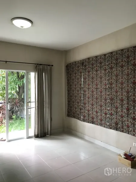 บ้าน ให้เช่าในLat Krabang, Bangkok - ห้องนั่งเล่นสว่าง พื้นกระเบื้องสีขาว ประตูกระจกบานเลื่อนและผ้าม่าน เปิดออกสู่สวนเขียวขจี